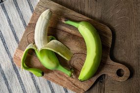 两个绿香蕉放在木砧板上