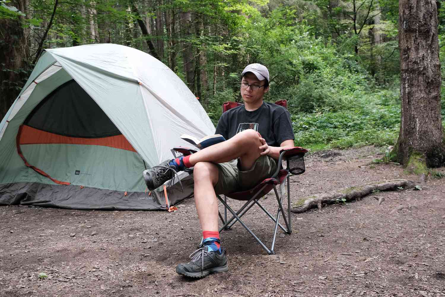 这家伙在户外露营时坐在帐篷旁的躺椅上看书