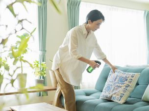 女人用绿色清洁剂喷洒软垫枕头和沙发。