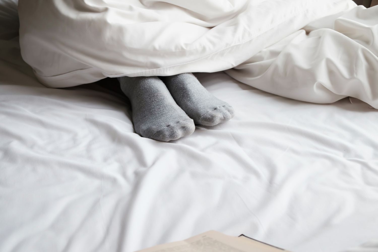 脚在灰色的袜子在床上部分覆盖着一个白色的被子