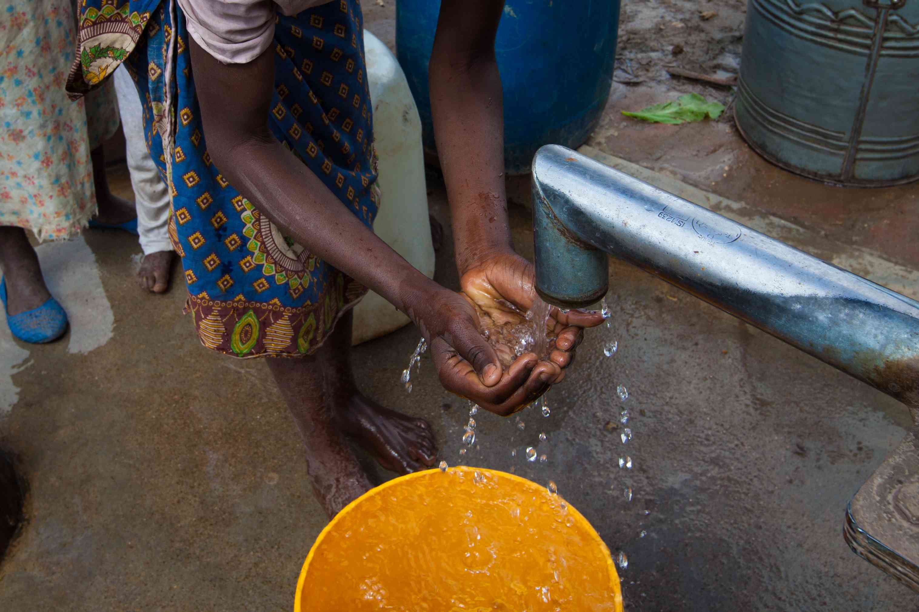 一个女孩在马拉维南部的一个钻孔上洗手“width=
