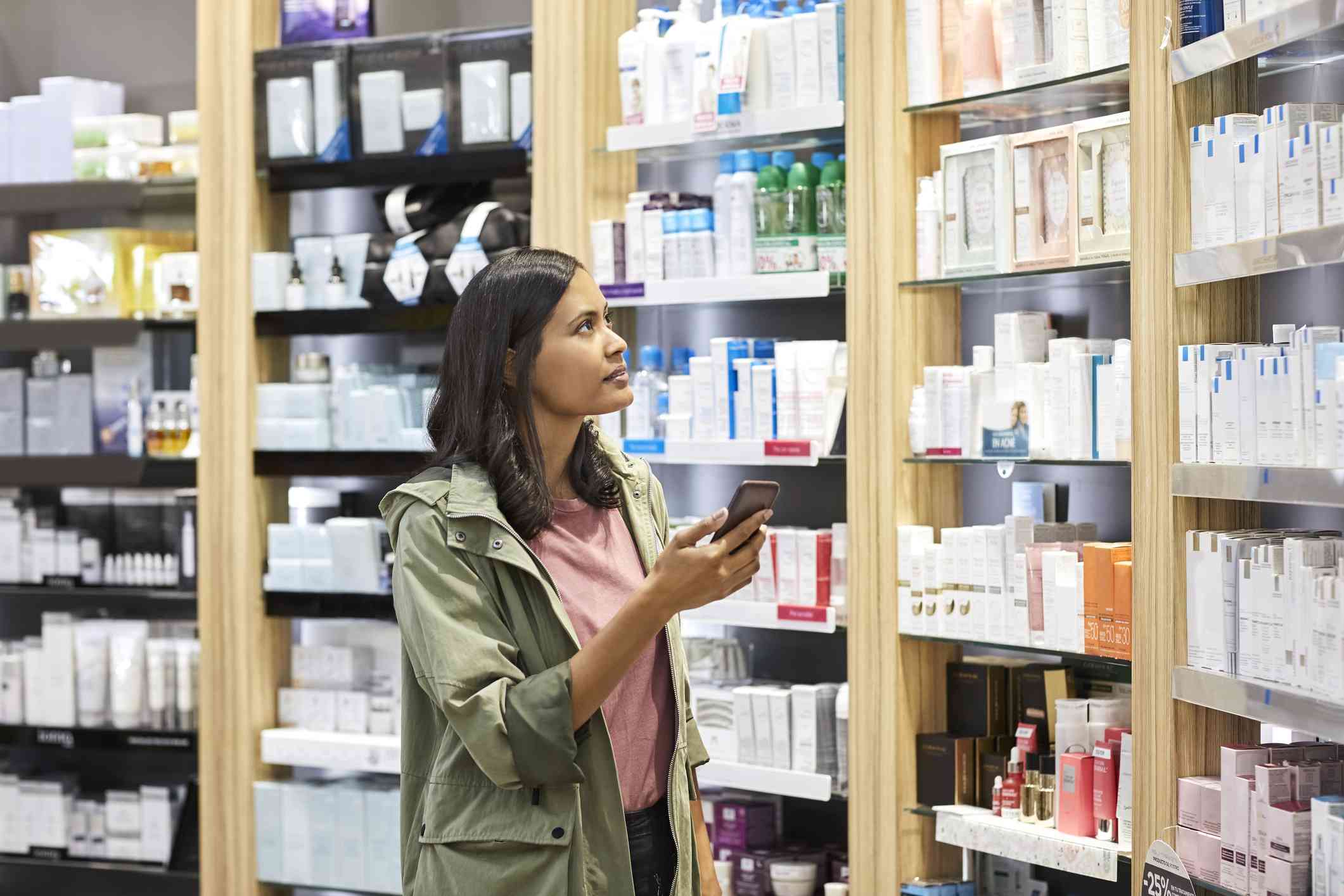 一名亚洲妇女拿着手机看着药品美容产品。