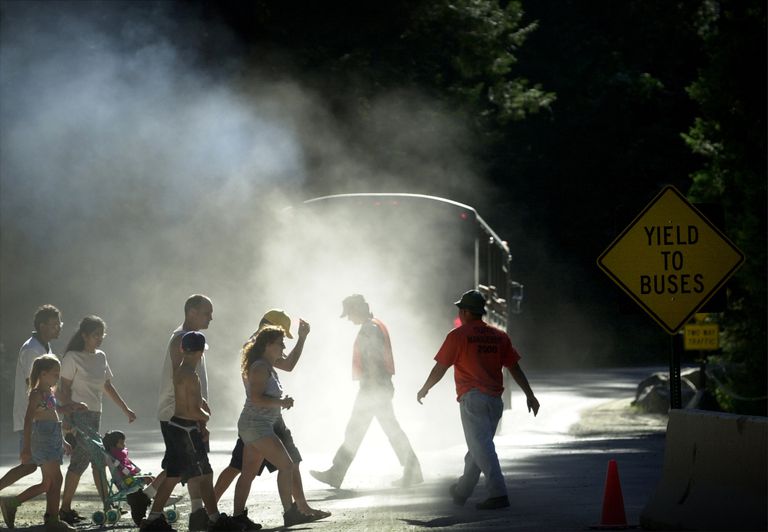 2000年6月16日，加州约塞米蒂国家公园，行人在约塞米蒂村附近穿过一辆公交的灰尘和柴油尾气。