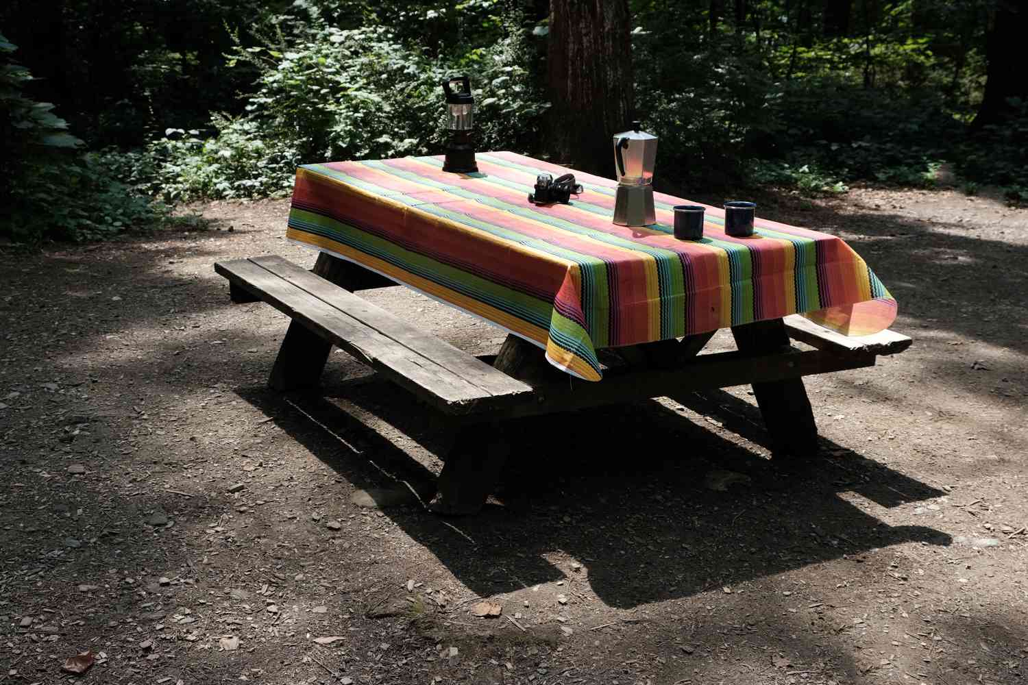 露营地的野餐桌，铺着五颜六色的桌布，还摆着咖啡