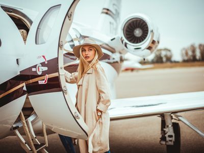 年轻富有的金发女性进入一个私人飞机停在机场的停机坪上。