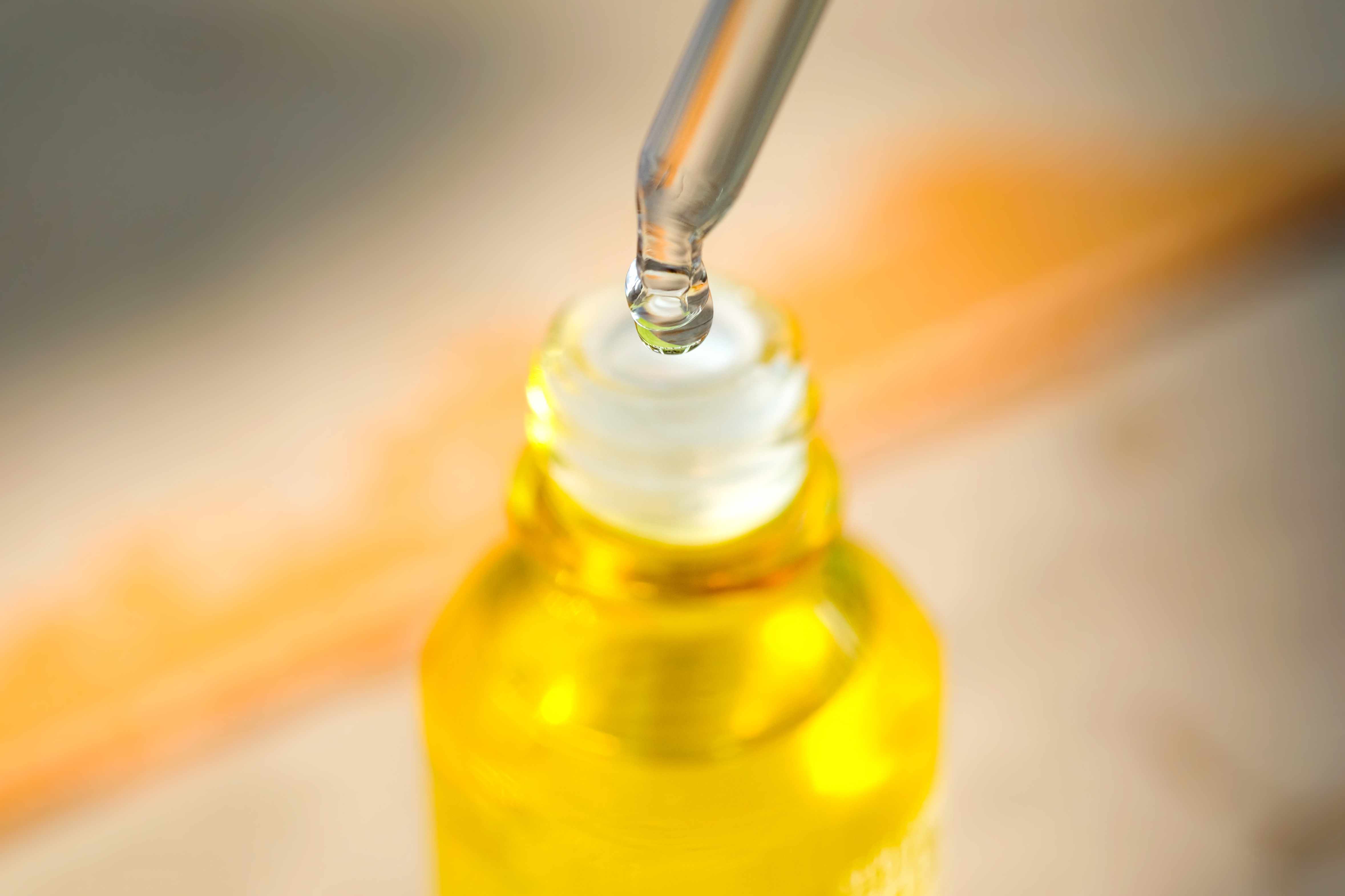 将血清胶原蛋白保湿液滴入透明黄色瓶中，背景柔和。保护皮肤护理面部精华油，维生素c，美容和水疗概念