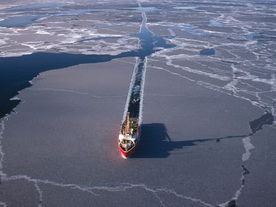 一条船的路径穿过北极海冰在一个阳光明媚的一天。