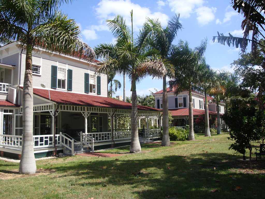 白色的房子，门廊上有红色的屋顶，前面有棕榈树