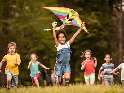 大群快乐的孩子们跑在春天放风筝。