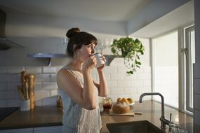 在零浪费厨房里用杯子喝水的女人