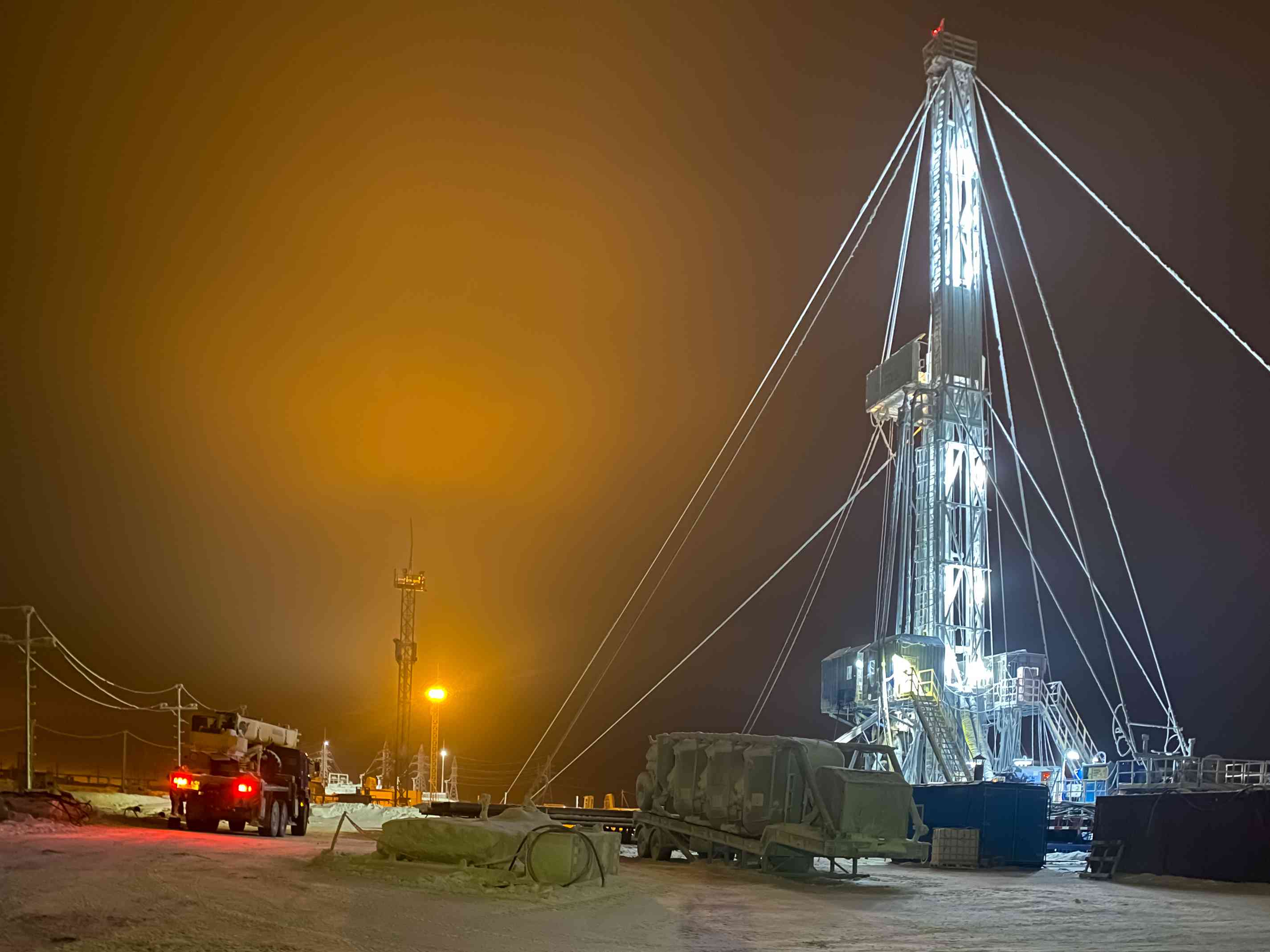 一个冬夜，俄罗斯北部的一个石油钻塔被明亮的灯光照亮。＂width=