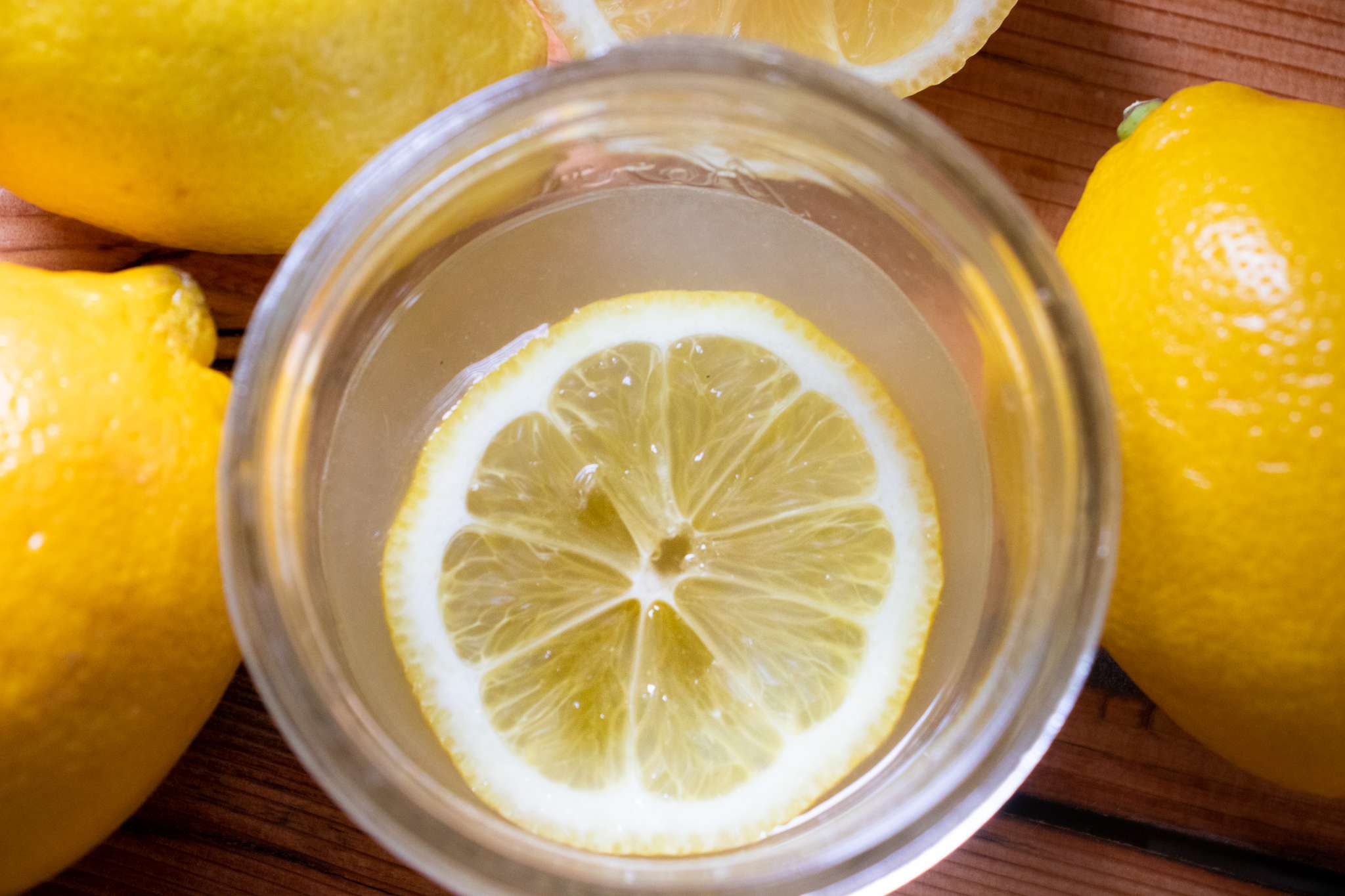 柠檬片漂浮在玻璃包围着整个柠檬”width=