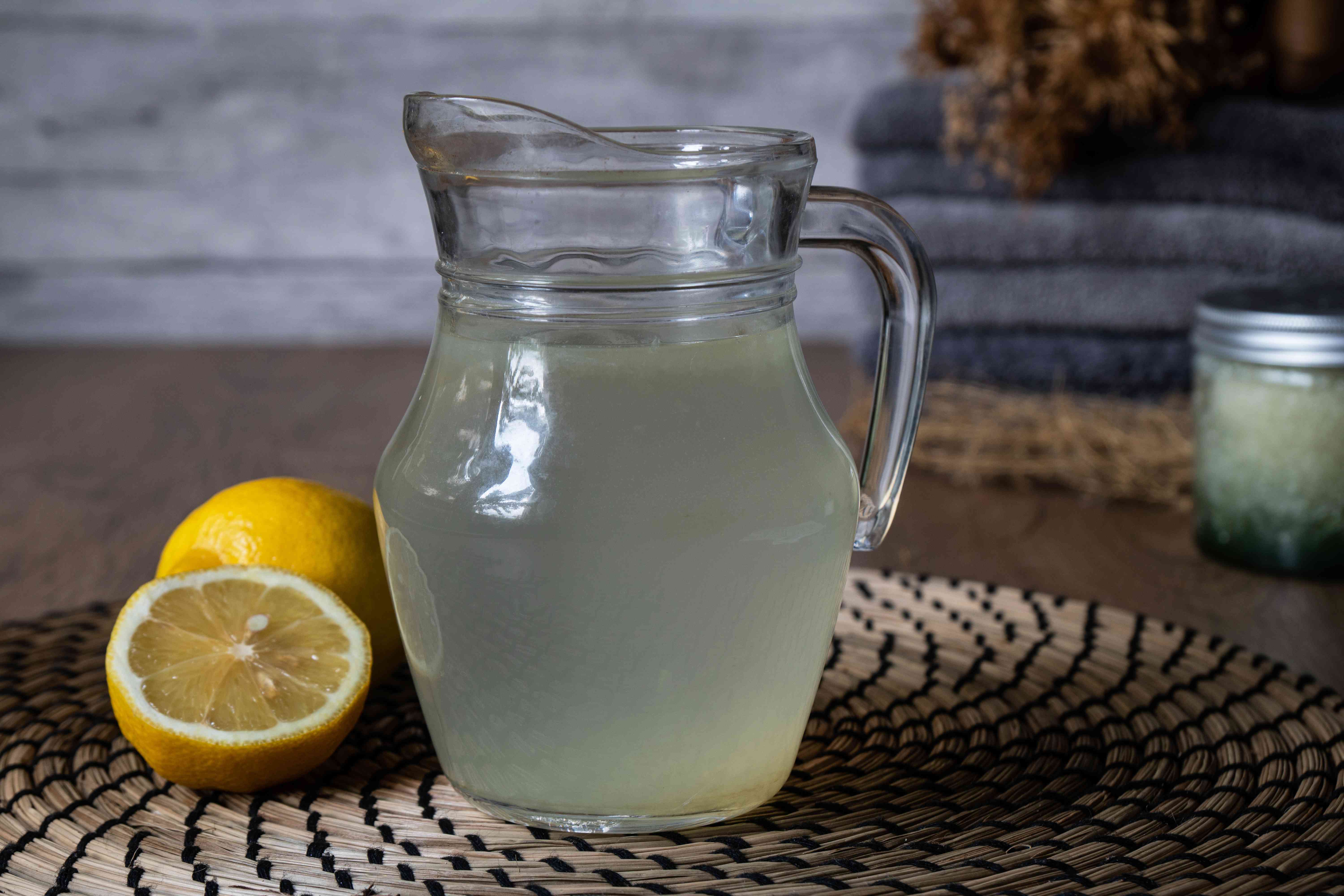 大的玻璃水罐装满柠檬汁和水，附近有新鲜切好的柠檬＂width=