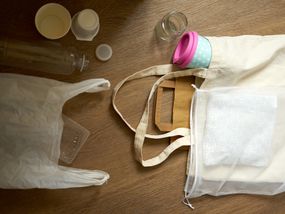 将塑料袋、可重复使用的袋子、可重复使用的咖啡杯和塑料物品平放“width=