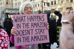 一位老妇人举着牌子，上面写着＂What happens in the Amazon doesn't stay Amazon