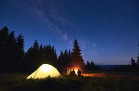 露营者在星光灿烂的夜空下，帐篷被照亮