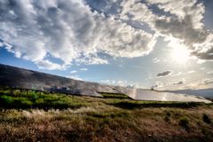 在日落附近的西科罗拉多的一个太阳农场与阳光，反射在太阳电池板的蓝天和云彩