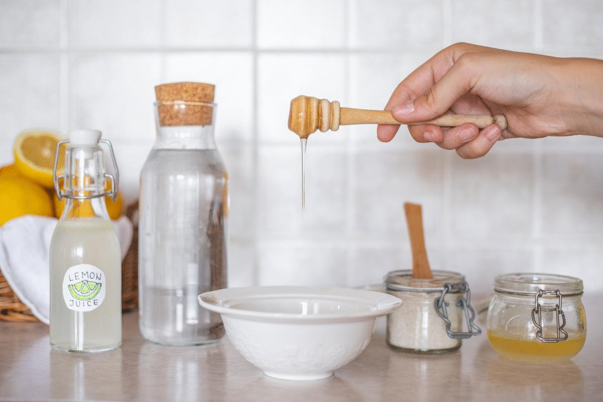 手将蜂蜜从木滴漏器中滴入碗中，放在燕麦片和柠檬汁旁边
