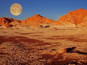 智利阿塔卡马沙漠中的夕阳下日落的满月。