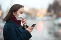 小女孩戴着防护口罩，用智能手机检查空气污染