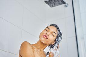 女人在淋浴间洗头发＂width=