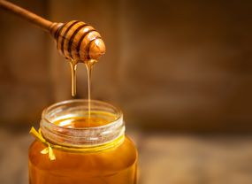 在一个玻璃瓶子的蜂蜜有蜂蜜浸染工的在土气木桌背景。复制空间。