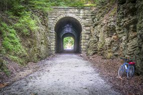 一辆自行车停在岩石墙上，旁边是一条穿过石头隧道的碎石小道