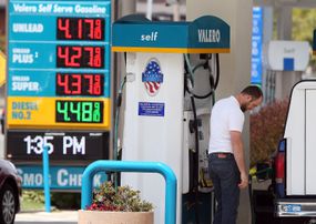 油价上涨的加油站广告牌和一个男人加油的画面。