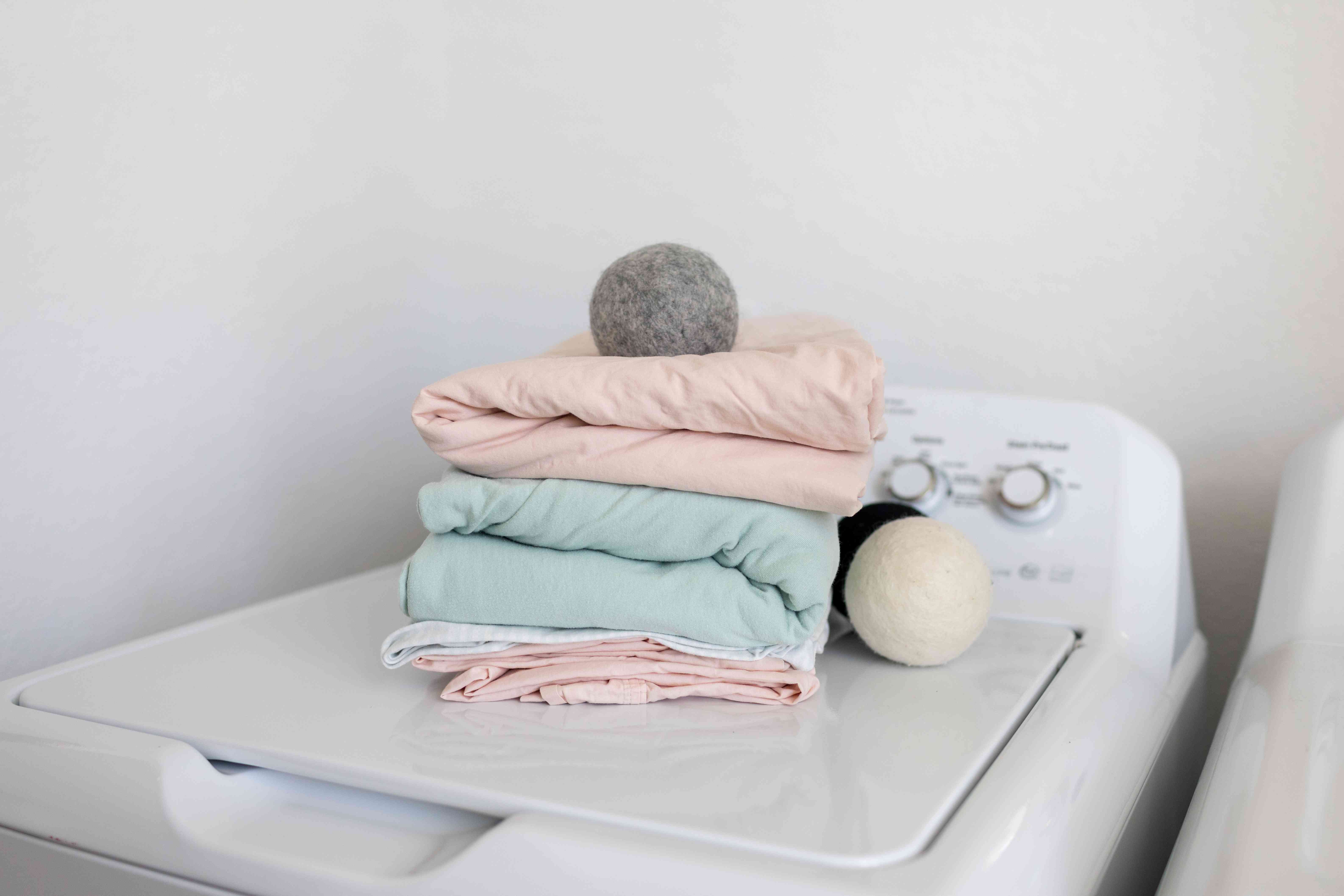 洗衣机顶部的折叠床单和羊毛干球