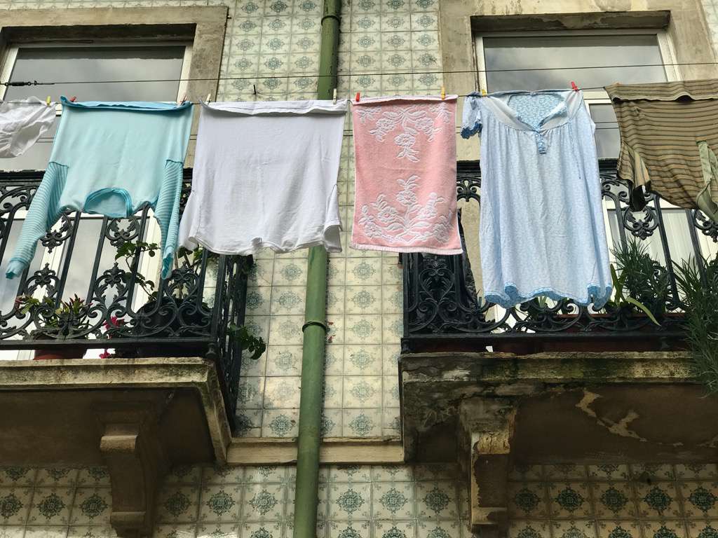在葡萄牙里斯本，室外挂在电线上的衣服。＂width=