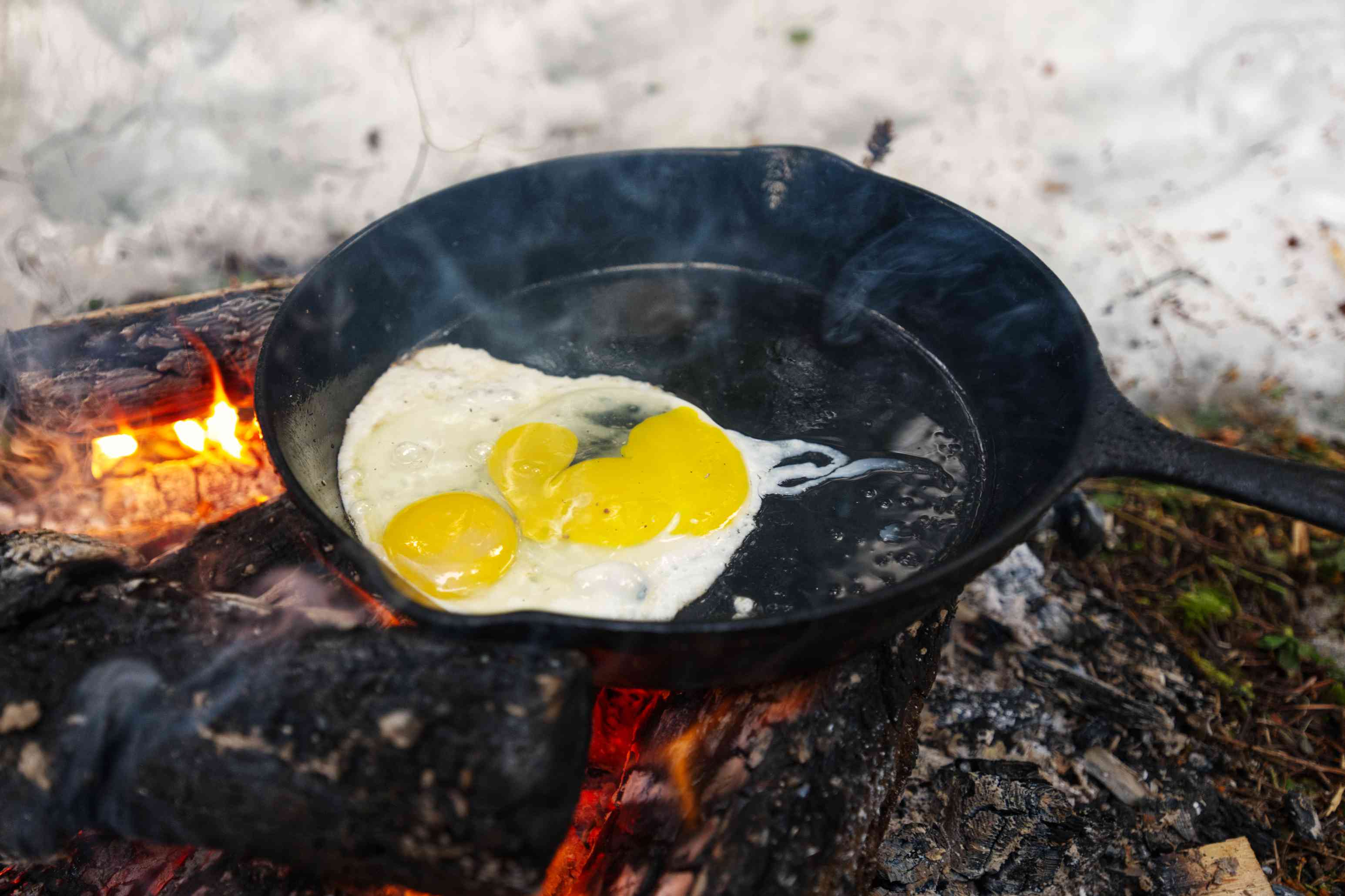 在雪地里的篝火上用铸铁煎锅煮鸡蛋