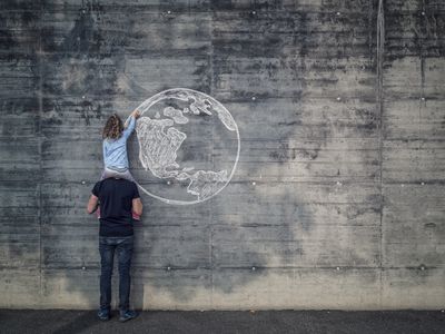 奥地利萨尔斯堡,父亲和女儿在自己的肩膀上,女儿用粉笔画地球在混凝土墙