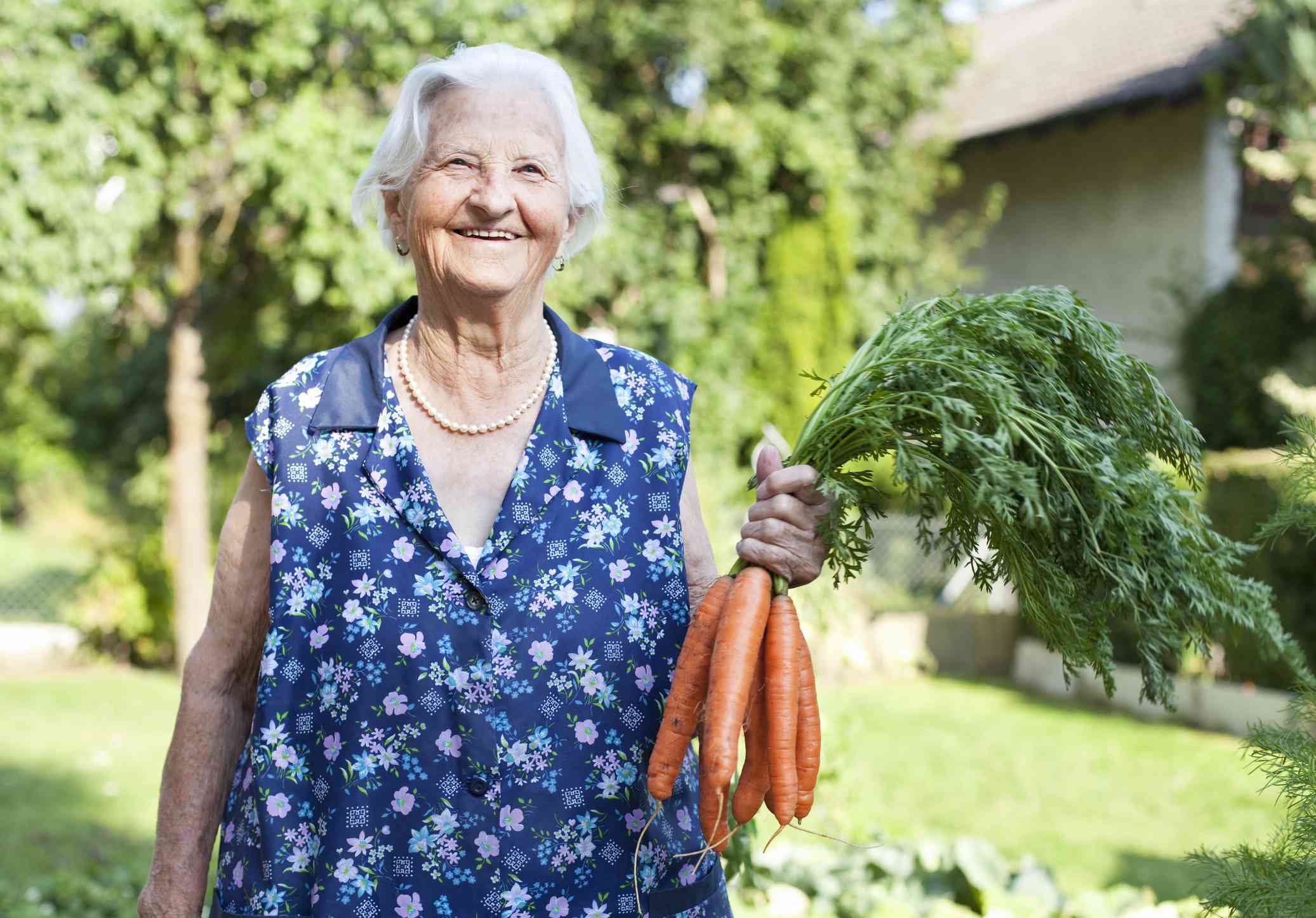 一名老妇人笑着抬起一堆胡萝卜。