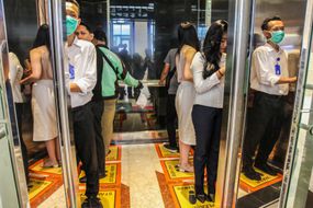 人们社会距离和戴着面具在电梯里