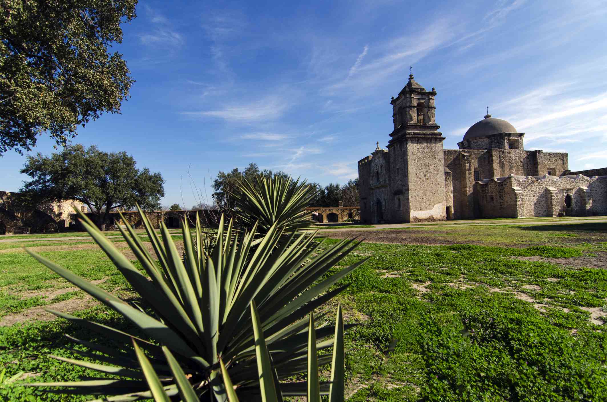 圣何塞Y任务圣何塞Y San Miguel de Aguayo位于蓝天下方的远处，浅云，绿草和低植物在前景