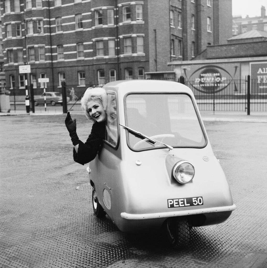1962年11月8日，伦敦，在伯爵法院展览中心外，模特凯伦·伯奇在驾驶皮尔P50，这是一辆由曼克斯皮尔工程公司生产的新型微型汽车，摩托车展开始前。＂width=