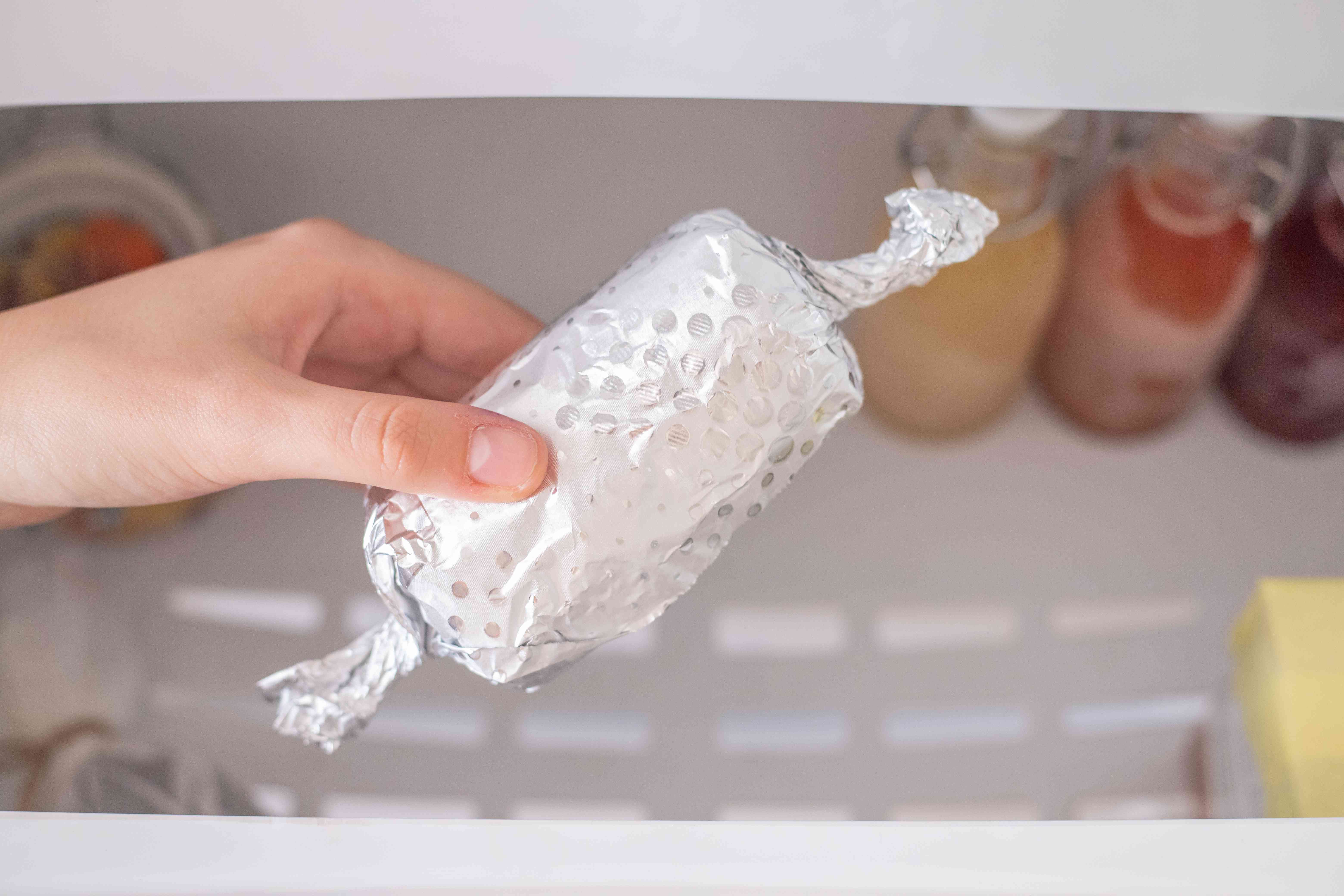 手伸出冷冻食品包裹在铝箔打开冰箱抽屉