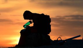 一个孩子看着他的水瓶，因为太阳于2021年6月15日在加利福尼亚洛杉矶落山，随着温度在早期的热浪中飙升。“width=