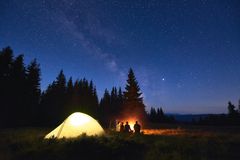 露营者在星空的夜空下，背后有照明帐篷