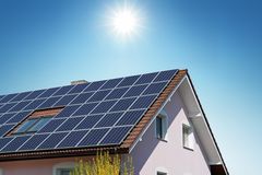 阳光照在太阳能电池板覆盖的房屋的屋顶上。
