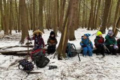 孩子们背着背包坐在森林学校的圆木上