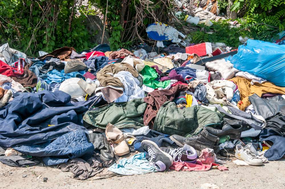 垃圾和垃圾堆放在草地上的旧衣服和鞋子