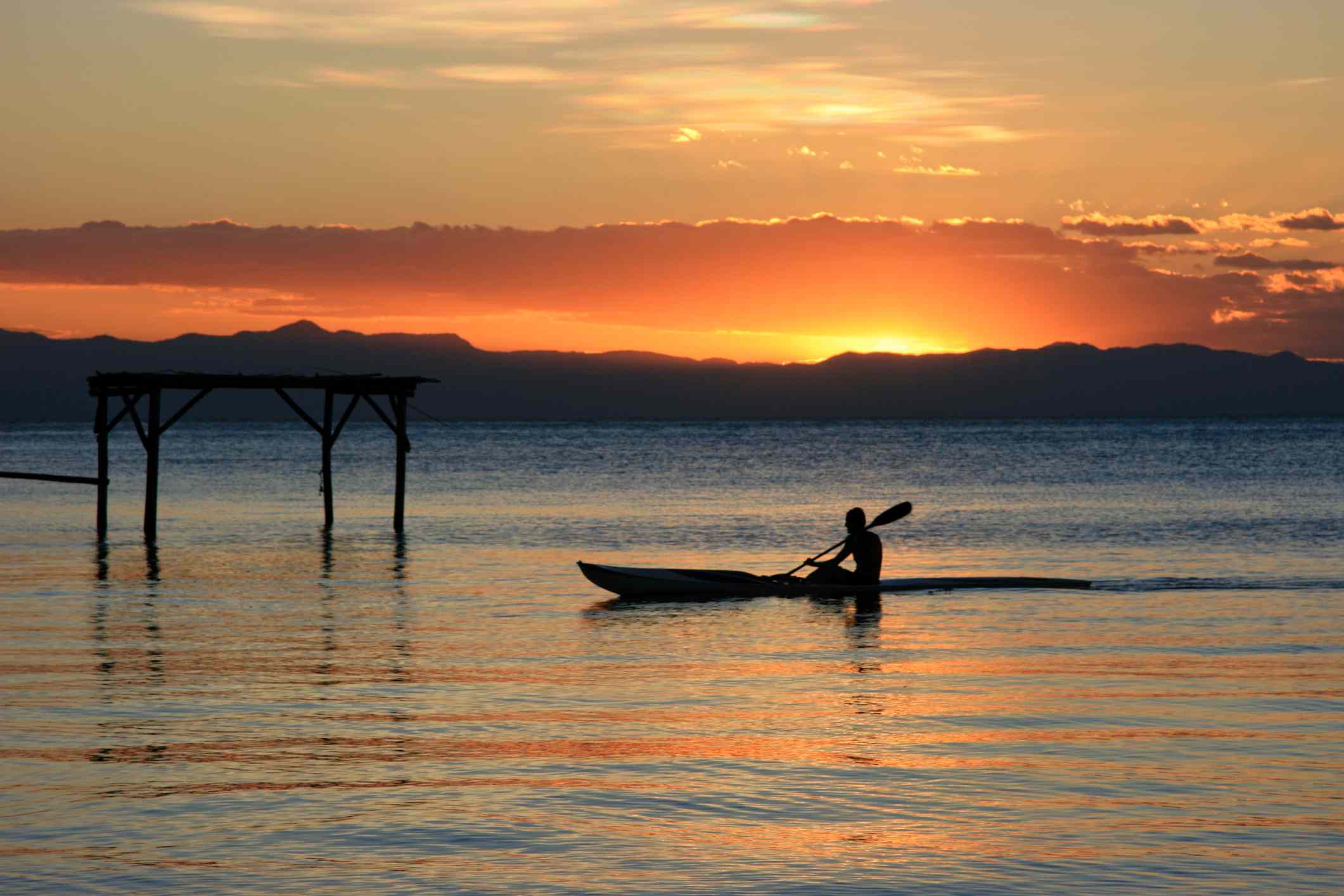 马拉维湖上的单人皮划艇，远处是鲜艳的橘色和黄色夕阳