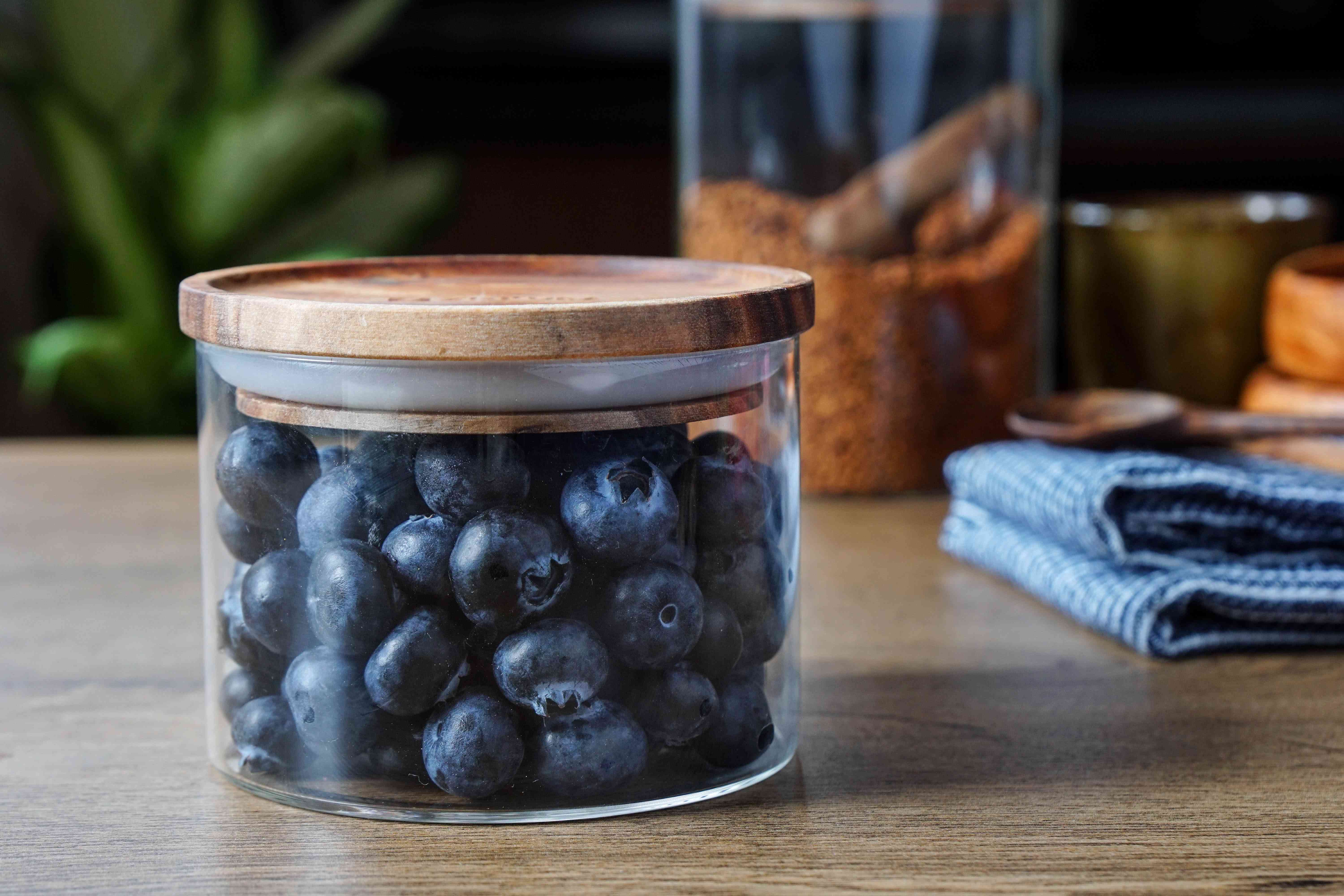 玻璃储物容器，装满蓝莓，顶部有木制橡胶盖