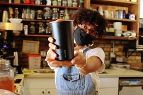 barista holds out reusable Muuse coffee cup