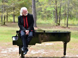查克·里维尔坐在树林里的钢琴上。