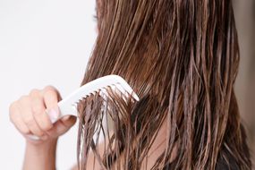 一个女人用宽牙梳子梳理湿头发。