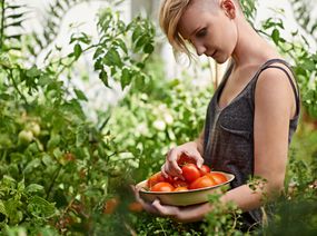 一个女人在看新鲜的西红柿“width=