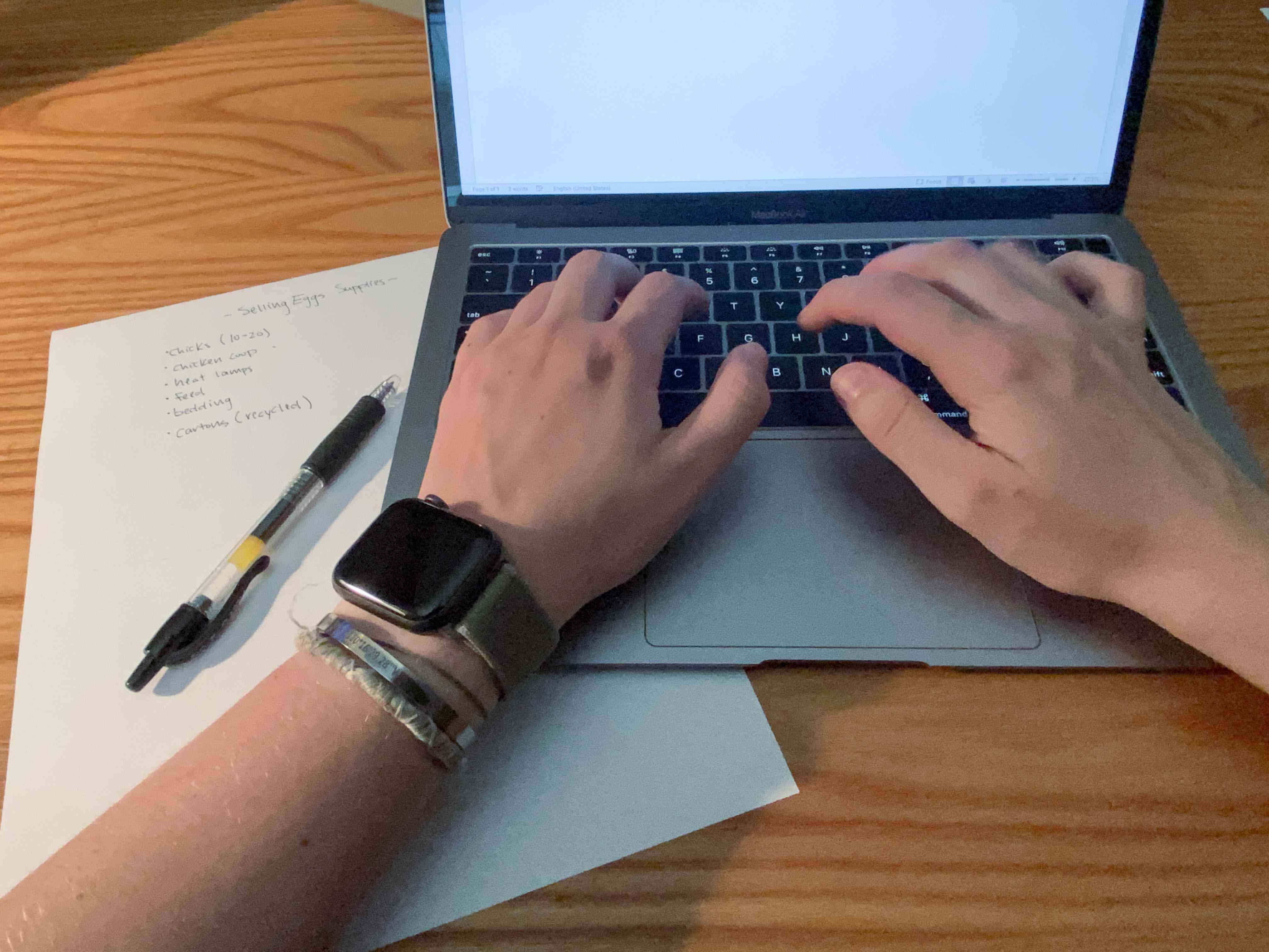 Apple Watch的人在笔记本电脑上使用笔记编写业务计划