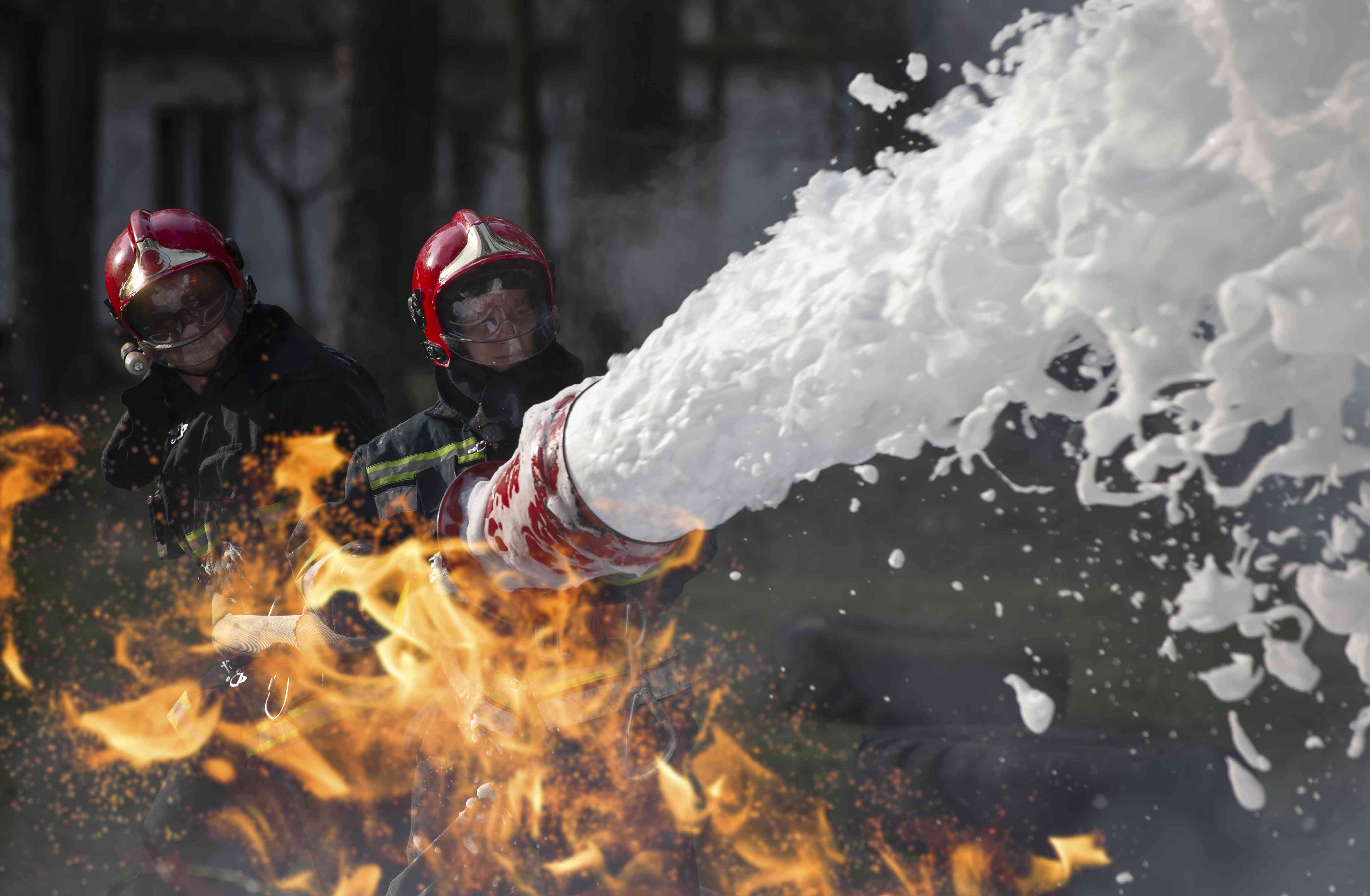 消防队员正在灭火。救生员用消防水管在烟雾和火灾中灭火。“width=